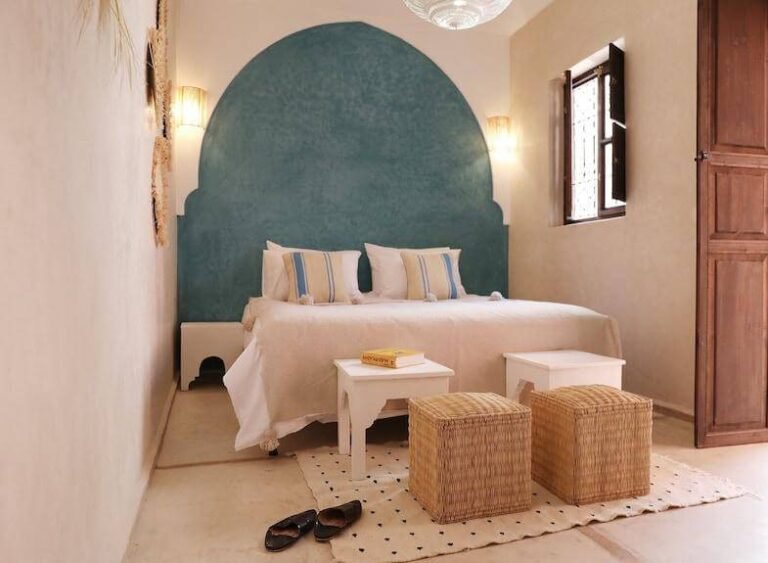 Chambre apaisante aux tons beige et bleu tendre, ornée d’une œuvre d’art au Dar Nour el Houda à Marrakech.