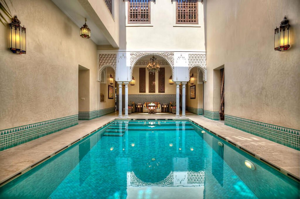 Courtyard swimming pool at Riad Kniza surrounded by traditional Moroccan architecture