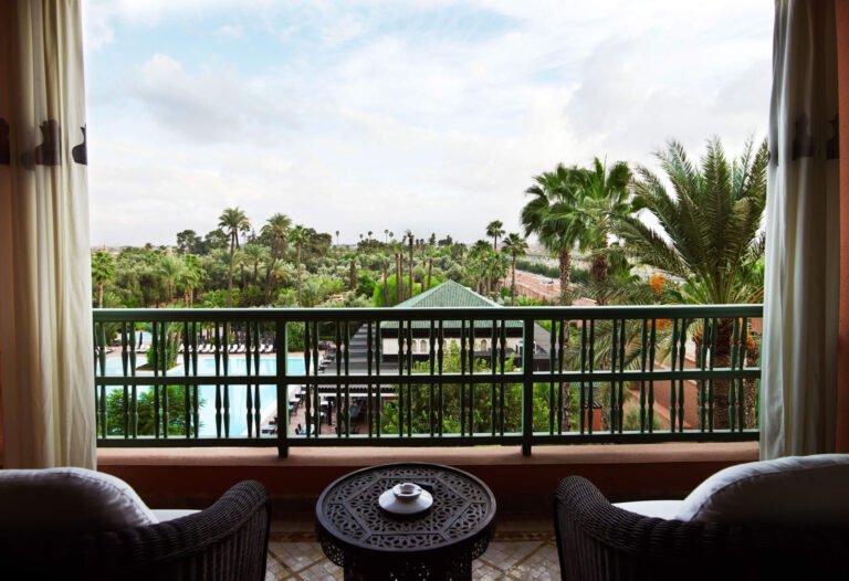 Balcony view from La Mamounia overlooking lush gardens and Marrakech skyline