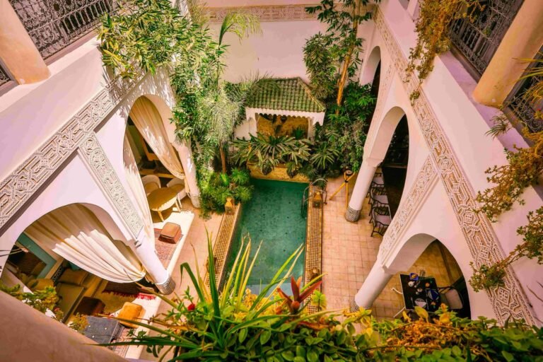 Riad Dar Saad courtyard with traditional Moroccan tiles, lush greenery, and a tranquil seating area in Marrakech Medina