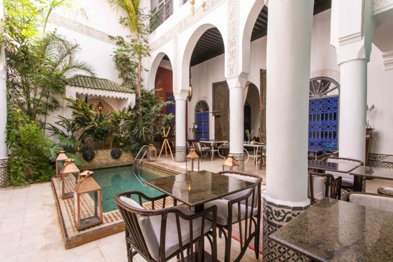 Riad Dar Saad courtyard with traditional Moroccan tiles, lush greenery, and a tranquil seating area in Marrakech Medina