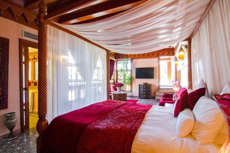 Chambre d’hôtes de style marocain avec lit à baldaquin au Riad Jnane Mogador à Marrakech.