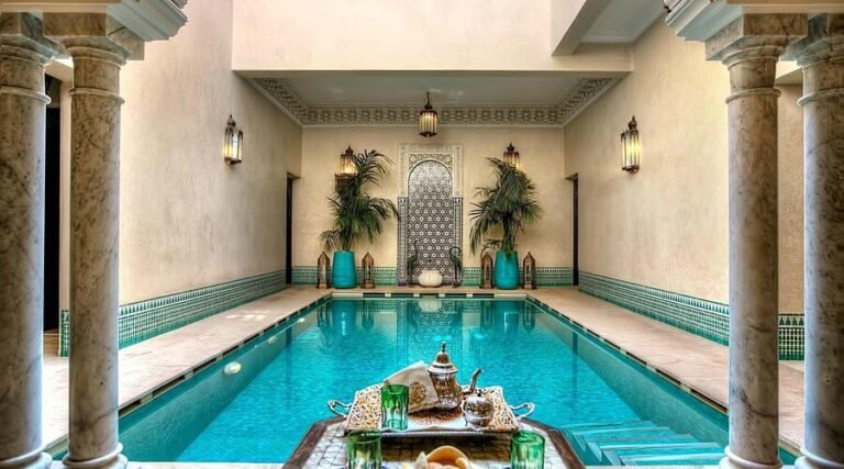 Riad Kniza Marrakech traditional courtyard with carved wood, zellige tiles and pool