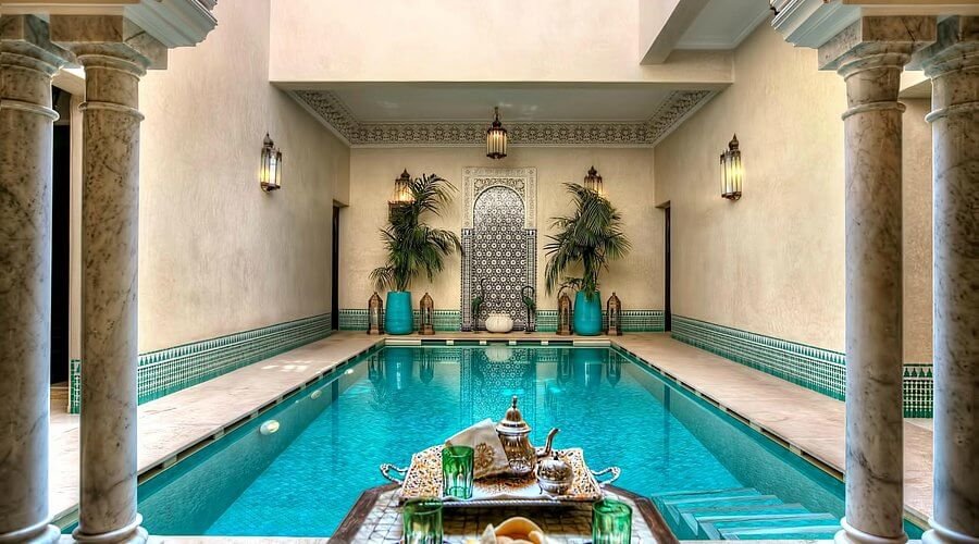 Cour traditionnelle du Riad Kniza Marrakech avec bois sculpté, zelliges et piscine