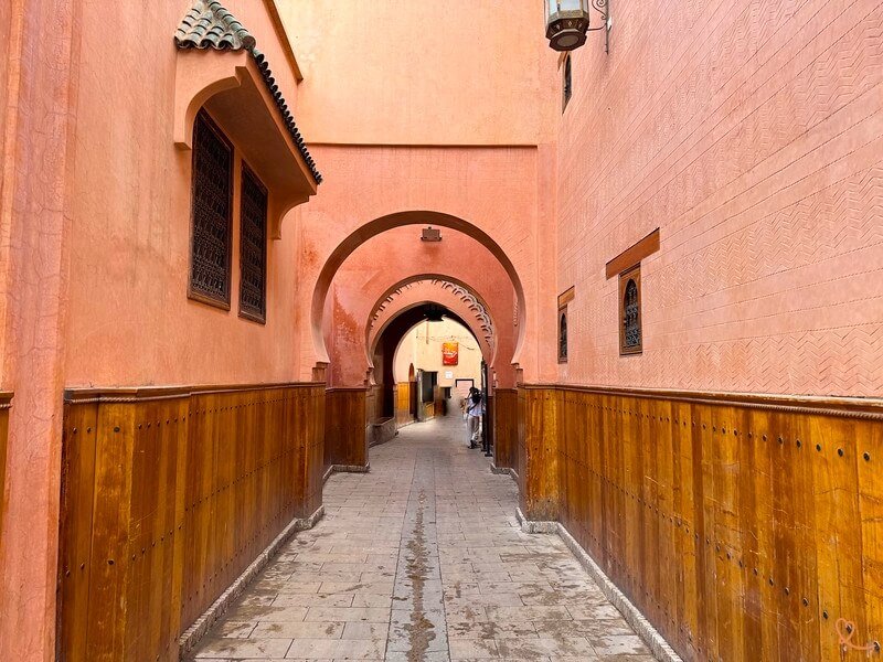 Ruelle rose et calme au nord de la Médina de Marrakech, avec passages voûtés et lambris de bois sculpté