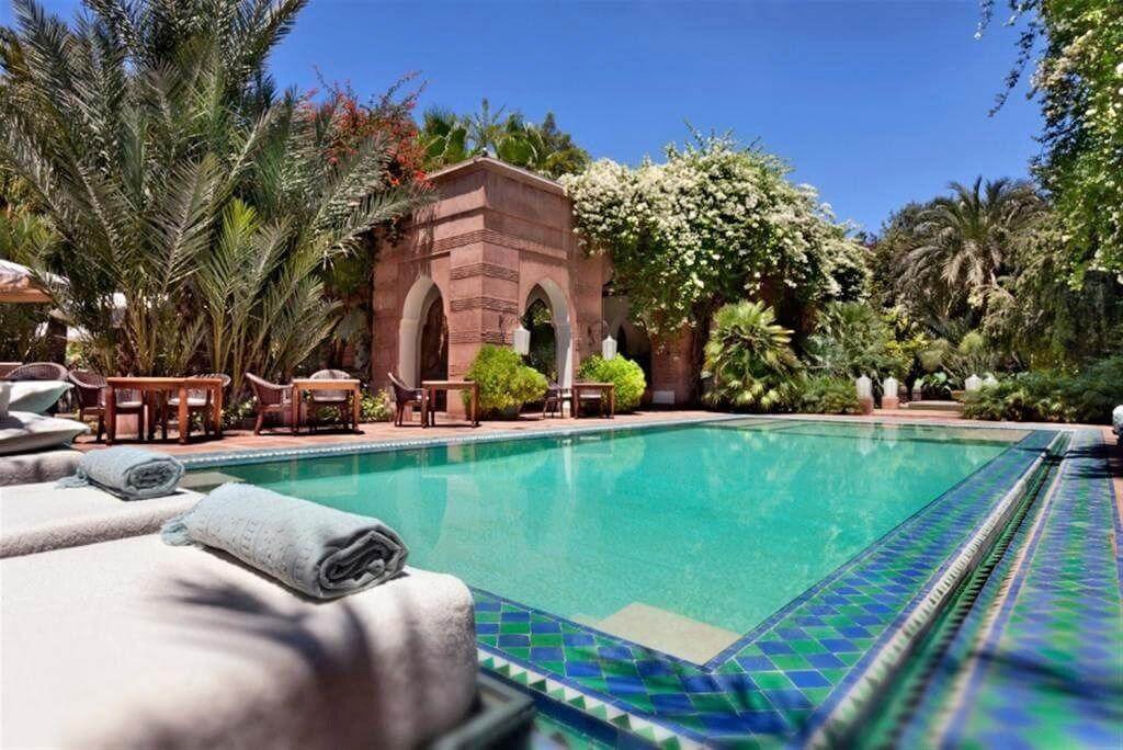Piscine extérieure entourée de jardins luxuriants et d’une élégante architecture de style palais au Dar Rhizlane à Marrakech.