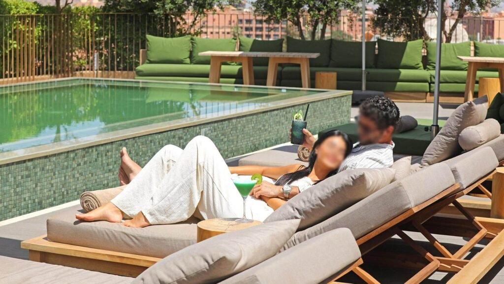 Piscine sur le toit entourée de végétation au Jadali Hotel & Spa à Marrakech, avec une vue panoramique sur la ville.