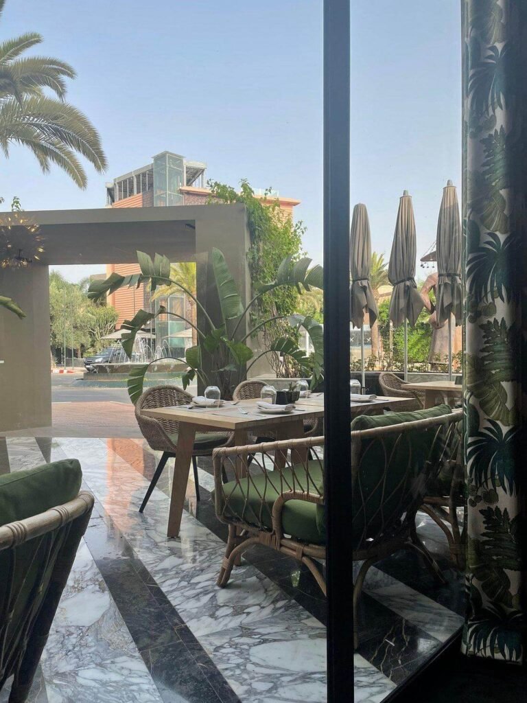 Terrasse sur le toit ALMA avec mobilier en osier et végétation luxuriante au Jadali Hotel & Spa à Marrakech.