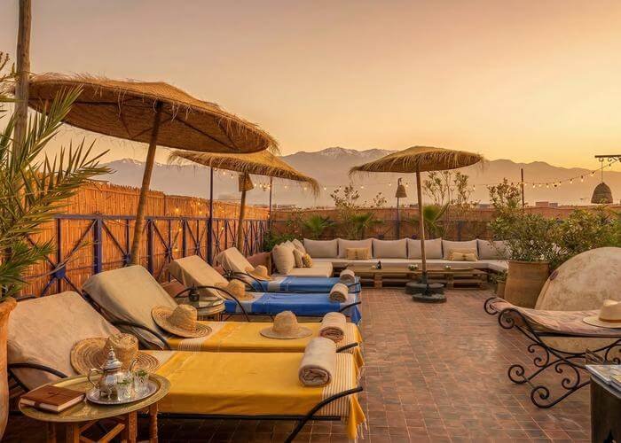Rooftop terrace with sun loungers and views towards the Atlas Mountains at Riad Azawan in Marrakech.