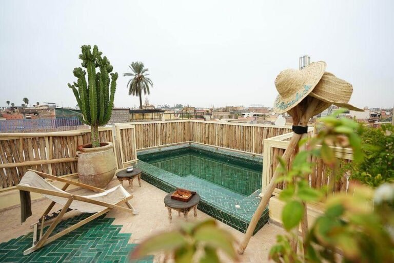 Piscine sur le toit entourée de chaises longues au Riad Nouceiba à Marrakech.