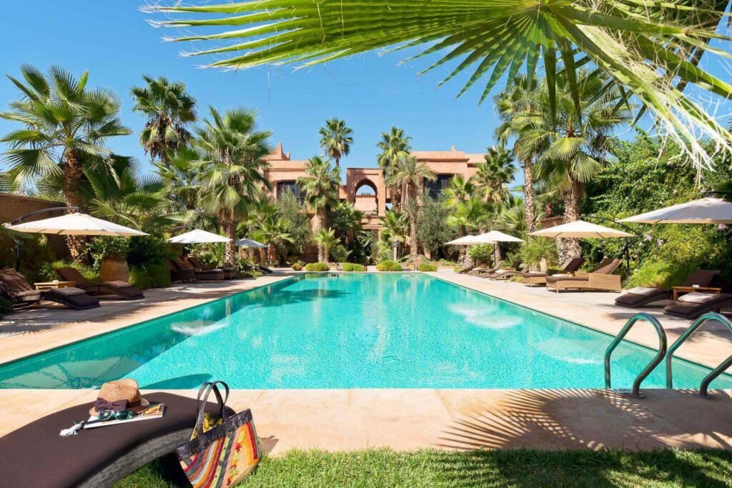 Piscine extérieure entourée de palmiers et de jardins luxuriants au Tigmiza Boutique Hotel & Spa à Marrakech.